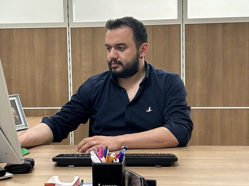 Op. Dr. Doruk Taş, lacivert gömleğiyle masasında çalışırken